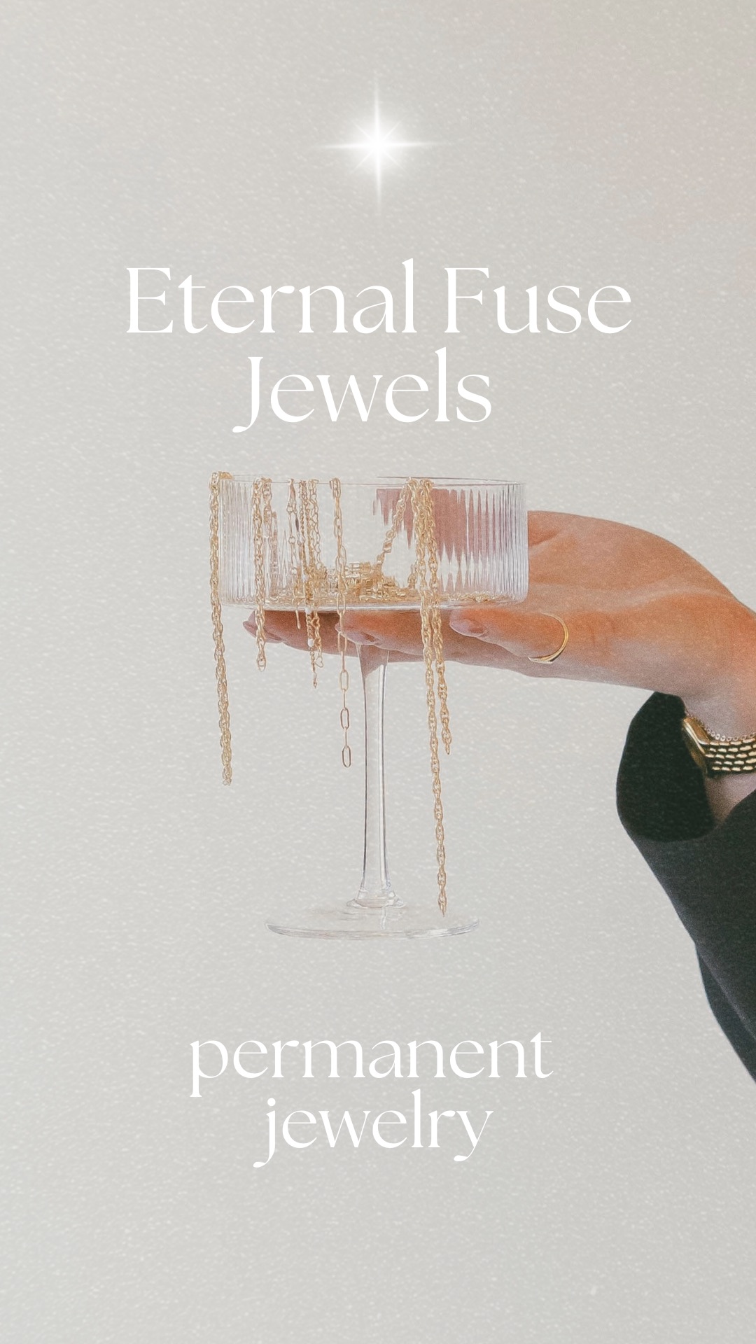 A hand holds a glass overflowing with layered gold permanent jewelry chains under a starry night sky
